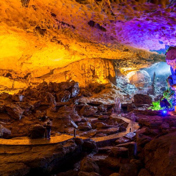 Inside Sung Sot Cave with colorful lights illuminating stalactites and stalagmites